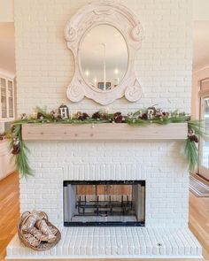 a white brick fireplace with greenery and a mirror above it