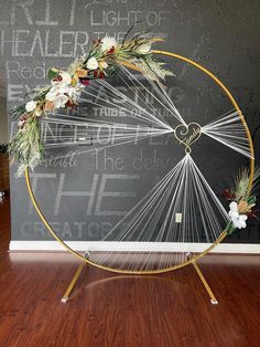 a hammock wheel decorated with flowers and greenery in front of a chalkboard wall