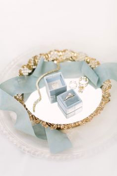 two wedding rings are sitting on a plate with blue ribbons and bows around it's edges