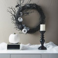 a white pumpkin sitting on top of a table next to a wreath and candle holder