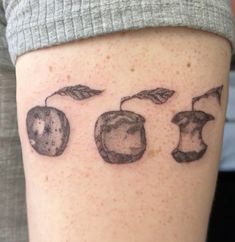 an apple tattoo is shown on the leg of a person's arm, which has three apples and leaves drawn on it