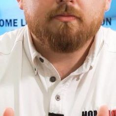 a close up of a person wearing glasses and a white shirt with black lettering on it