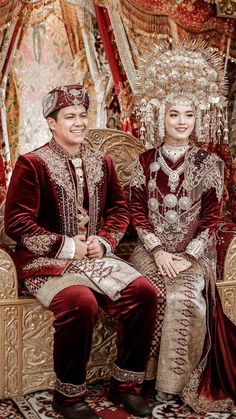 a man and woman dressed in elaborate clothing sitting next to each other