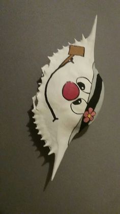 a paper mask with a clown face on it's side and a flower in its mouth