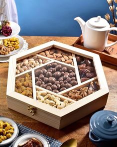 a wooden box filled with nuts on top of a table next to plates and cups