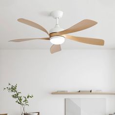 a white ceiling fan with wooden blades in a living room next to a table and chairs