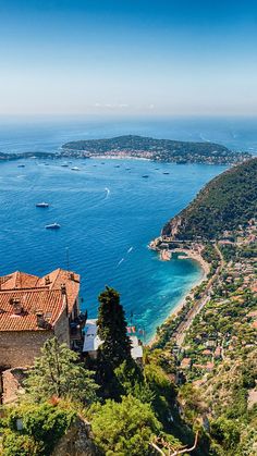 an aerial view of the ocean and coastline with boats in the water, surrounded by trees