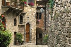 an old stone building with potted plants and flowers on the balconies above it