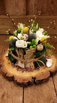 an arrangement of flowers is placed on top of a piece of wood