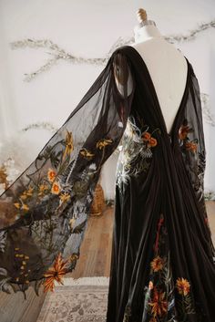 a black dress with flowers on it sitting on a mannequin