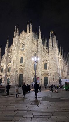 people are walking around in front of a cathedral