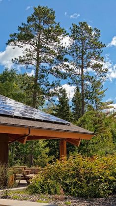 a small building with a solar panel on the roof and trees in the back ground