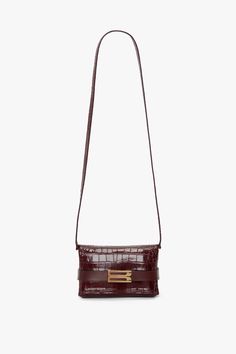 The brand’s signature Mini Chain Pouch silhouette is reimagined with a B buckle belt detail for AW24. Functional and decorative, the belt detail wraps around the body of the bag, holding the pouch securely closed. Crafted from calf leather with a supple embossed crocodile print, it is presented in burgundy and lined in sumptuous suede for a tactile finishing touch. A detachable crossbody strap allows for versatile styling. Victoria Beckham Exclusive Mini B Pouch Bag In Croc Embossed Burgundy Lea Designer Rectangular Formal Belt Bag, Designer Formal Rectangular Belt Bag, Designer Formal Pouch Belt Bag, Belted Crossbody Bag As Fashion Accessory, Elegant Satchel Belt Bag For Office, Luxury Office Belt Bag With Detachable Strap, Formal Satchel Belt Bag With Detachable Strap, Classic Rectangular Belt Bag For Formal Occasions, Classic Formal Rectangular Belt Bag