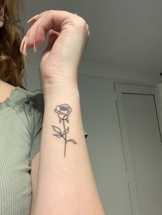 a woman's arm with a small rose tattoo on the left side of her wrist