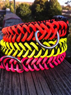 several different colored bracelets on top of a wooden table with metal rings attached to them