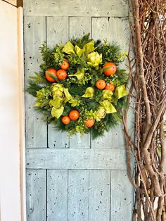 a wreath on the side of a door with oranges and greenery