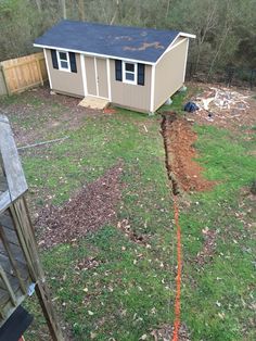 a backyard with a shed, fence and yard in the foreground is being worked on