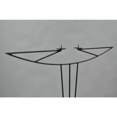 two birds are perched on the top of an iron sculpture in front of a gray sky