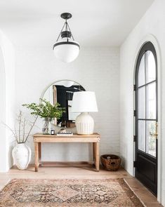 a room with a rug, mirror and lamp on the wall next to an arched doorway