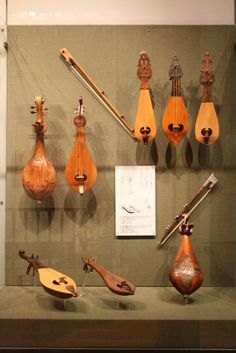 an assortment of musical instruments on display in a glass case, including mandolins and violines