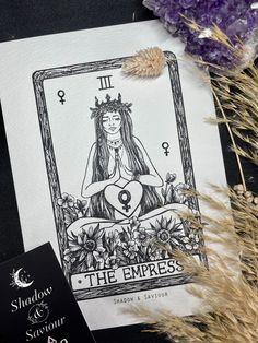 a tarot card sitting on top of a table next to some dried grass and flowers