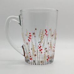 a glass coffee cup with red flowers painted on it