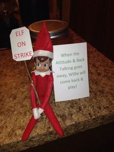 an elf holding a sign on top of a counter