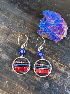 "Silver plated round 1\" hoops with horizontal lines of dark crimson/burgundy glass squares, 8/0 seed beads, deep blue and red and black mottled Picasso seed beads wire wrapped to the hoops. A silky sapphire blue carved glass flower bead lies at the top. Sterling ear hooks. 2 1/4\" x 1\". Matches the Crimson Blues Blossom Bracelet https://etsy.me/38sphwY" Bohemian Red Metal Hoop Earrings, Red Small Hoop Metal Jewelry, Small Hoop Red Metal Jewelry, Nickel Free Red Hoop Earrings, Red Metal Small Hoop Jewelry, Nickel-free Red Hoop Earrings, Artisan Nickel-free Red Earrings, Artisan Red Nickel-free Earrings, Red Bohemian Small Hoop Earrings