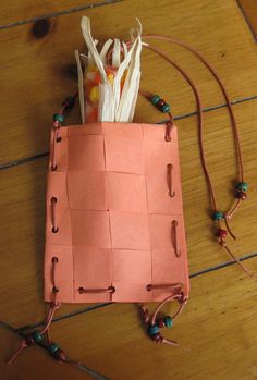 a bag made out of an orange piece of paper and some string on the floor