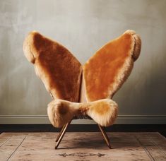 a chair with a butterfly shaped back rest on top of a wooden floor next to a wall