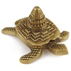 a gold colored turtle shaped object on a white background