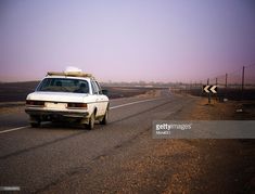 a white car driving down the road with an antenna on its roof in the desert