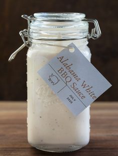 a jar filled with white sauce sitting on top of a wooden table next to a tag