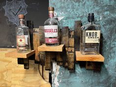 three bottles of alcohol sitting on wooden shelves