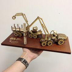 a hand holding a wooden tray with toy trucks on it