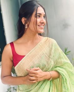 a woman wearing a green and yellow sari with a red top on her shoulders