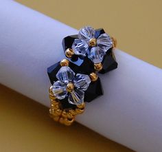 an image of two rings on top of a white napkin holder with beads and crystal stones