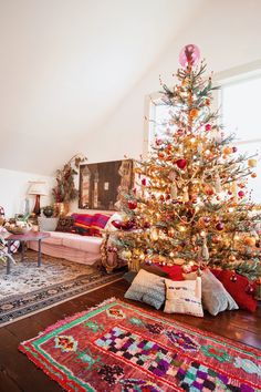 a living room with a christmas tree in the corner and rugs on the floor