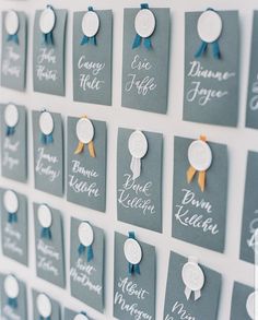 there are many tags on the wall that have names and ribbons attached to each one