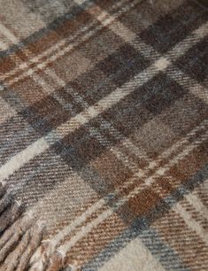 a brown and white plaid blanket laying on top of a bed