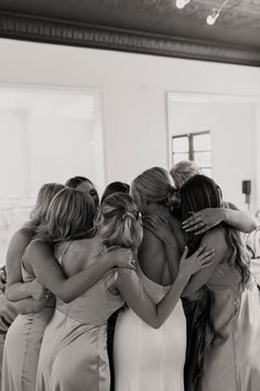 a group of women hugging each other in front of a mirror at a wedding ceremony