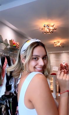 a woman standing in front of a closet holding up a piece of clothing and smiling at the camera