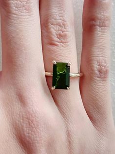 a woman's hand with a ring on it and a green stone in the middle