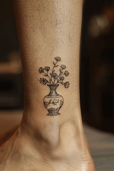 a woman's foot with a small tattoo on the ankle that has flowers in a vase