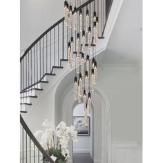 an elegant staircase with chandelier and flowers in vases on the floor next to it