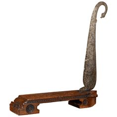 an old wooden bench with a metal hook on it's back end and long curved handle