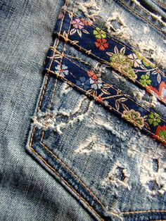 the back pocket of an old pair of jeans with colorful flowers on it and torn edges