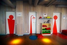 an empty room with red and green decorations on the walls, two doors open to reveal a child's playroom