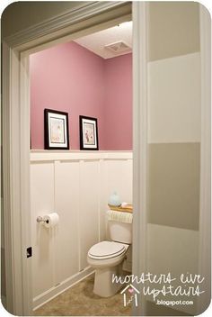 a white toilet sitting in a bathroom next to a pink wall with pictures on it