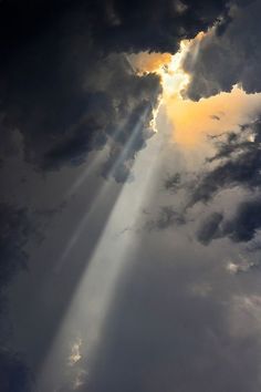 the sun is shining through clouds with light coming from it's beams in the sky